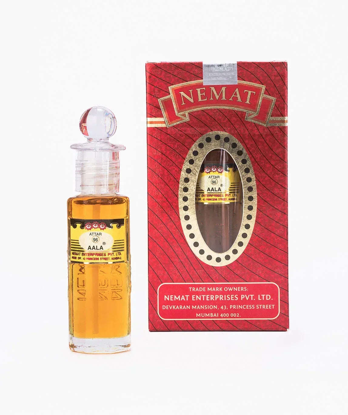 Attar perfume bottle with glass stopper next to decorative red perfume box